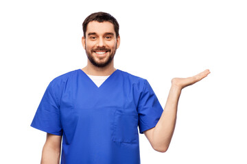 healthcare, profession and medicine concept - happy smiling doctor or male nurse in blue uniform holding something imaginary on empty hand over white background