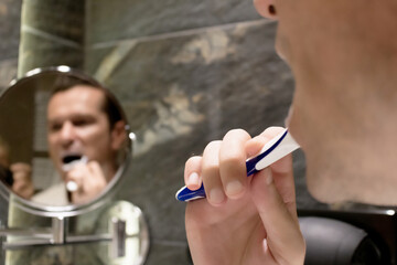 Close-up of man brushing teeth in the bathroom.