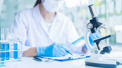 Fototapeta premium Medical or scientific researcher or man doctor looking at a test tube of clear solution in a laboratory
