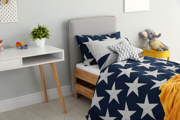 Bed with star patterned linens in child's bedroom. Interior design