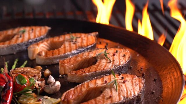 Grilled salmon fish with various vegetables on pan on the flaming grill