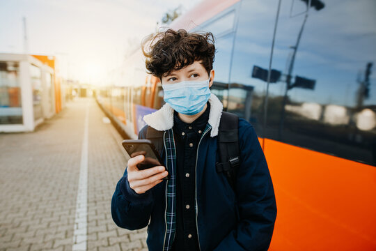 Reisen während einer Pandemie Junge mit Smartphone am Bahnhof 