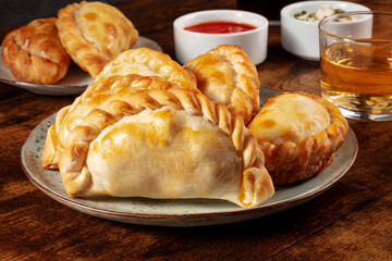 Empanadas with wine and various sauces on a dark rustic wooden background