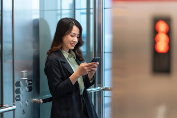 Portrait of young businesswoman standing in elevator and using phone © Timeimage