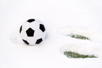 Classic soccer ball on a snowy sports ground and footprints in the snow. 