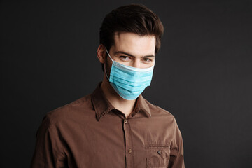 Pleased handsome young man posing in protective mask