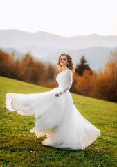 Young bride in wedding dress runing at sunset in the mountains