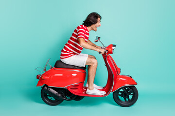 Fototapeta na wymiar Profile side view of handsome cheerful guy driving moped having fun hurry rush isolated over bright green turquoise color background