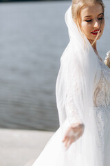 Fototapeta na wymiar Portrait of a gentle bride in a wedding dress near the river on a sunny day