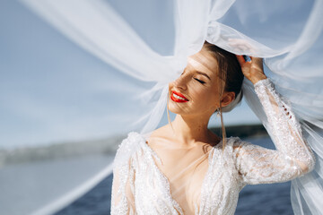 Portrait of a gentle bride in a wedding dress near the river on a sunny day