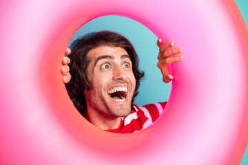 Close-up portrait of handsome cheerful amazed guy looking far through buoy having fun isolated over...