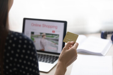 Close up of young woman shopper sitting by pc screen holding credit card preparing to make purchase online. Millennial female choose easy convenient secure electronic payment planning to get cashback