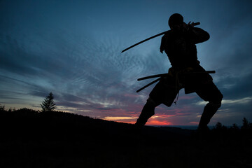 Silhouette of a Japanesesamurai with sword training during sunset - obrazy, fototapety, plakaty