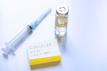 The syringe and the coronavirus vaccine are on the table. the concept of Free vaccination against coronavirus in the world in 2021. the inscription on the paper -  COVID-19 new vaccine.