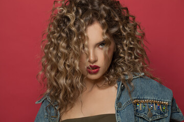 Perfect fashion model woman with curly hairstyle on red background