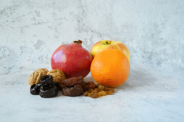 Apple,orange,pomegranate,prunes, walnuts, dried apricots, raisins in compartment on gray concrete background.  Healthy food and healthy lifestyle. Fruits as source of vitamins during winter time.