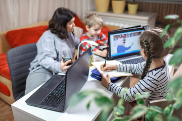Kids doing homework and mother working online in one room, distant education at home - obrazy, fototapety, plakaty