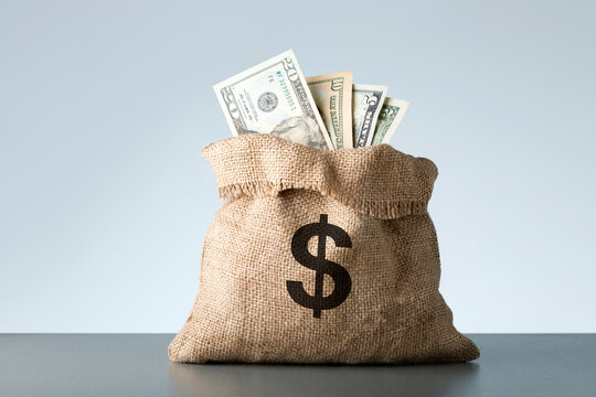 Burlap with dollar banknotes on gray background. Bribe or bonus concept.