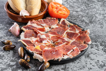 Close up of jabugo serrano ham slices with acorns, tomatoes, garlic and olive oil, Dry Spanish ham....