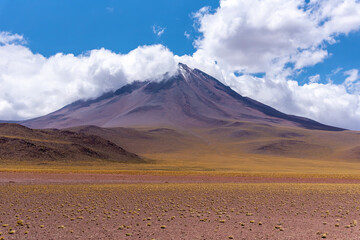 Fototapeta premium Licancabur volcano with snowy peak located against cloudy blue sky in Atacama Desert, Chile