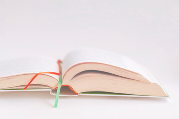 Open book close-up with colorful bookmarks on background of pink color tone. Selective focus