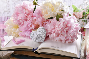 shabby chic style love arrangement with pink peonies and a heart lying on old books