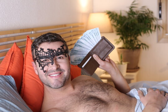 Very attractive man in bed with full wallet 