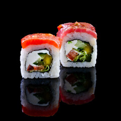 Concept of Asian cuisine. Two rolls of sushi with different fillings on a black background for Japanese menu. two sushi rolls couple isolated with reflection