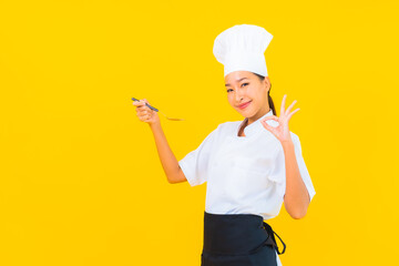 Portrait beautiful young asian woman wear chef or cook uniform with spoon and fork
