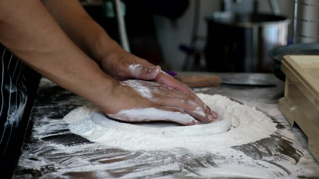 Chef is cooking floured hands is kneading dough italian pizza. Making and preparing dough for homemade bakery. Process of making pizza at table.
