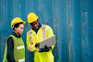 worker team man and woman in protective safety jumpsuit uniform with yellow hardhat and use laptop check container at cargo shipping warehouse. transportation import,export logistic industrial service