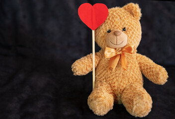 Teddy bear with a big red heart on a dark background. Place your own text over the heart or to the side of the bear