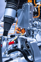 Chassis of the electric car with powertrain and power connections closeup. Blue toned. EV car drivetrain at maintenance.