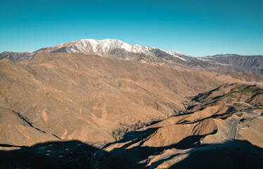 Amazing panoramic view of a serpentine road crossing the Atlas Mountains in Morocco with snow on the peaks