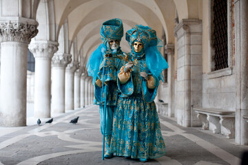Fototapeta na wymiar Masked couple in ornate costume at the the Venetian masquerade stands near St. Mark's Square in Venice