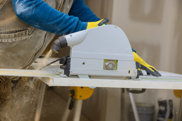 Wood contractor using an electric saw to cut door trim boards on the construction of a new home