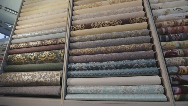 Wallpaper with patterns. Stands with rolls of wallpaper samples in the store. Stands with new samples. Rolls with wallpaper. Closeup