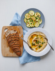 homemade sourdough bread, hummus, zucchini, veggie food, vegetables, natural food, healthy food, on a cutting board and a blue napkin, rustic style, homemade food