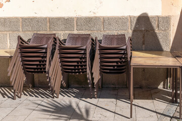 Fototapeta na wymiar Brown plastic chairs stacked next to outdoor tables
