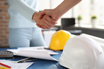 Over construction sketches, designer and client shake hands with each other