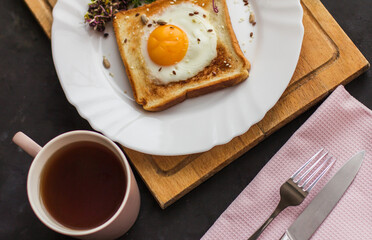 A sandwich with egg in the hole of the bread, microgreens, healthy food Breakfast, a cup of tea