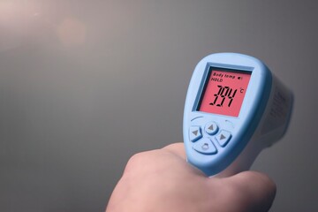 Unrecognizable person holding a digital body temperature detection device. Horizontal image with...