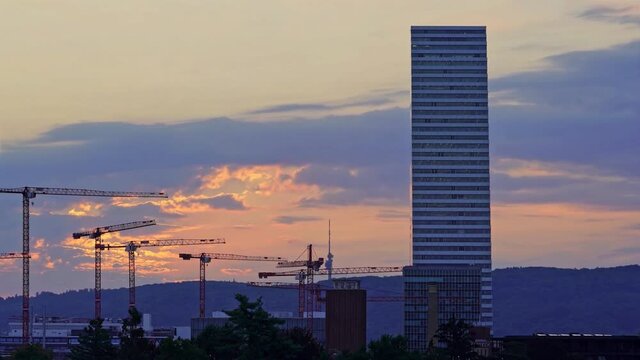 Time-lapse of construction site at sunrise, a building under construction and many cranes