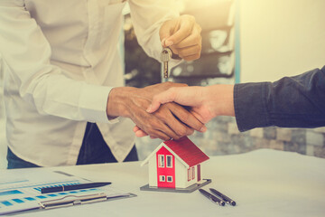 Salesman giving key house to customer in concept business loan finance investment family rent...