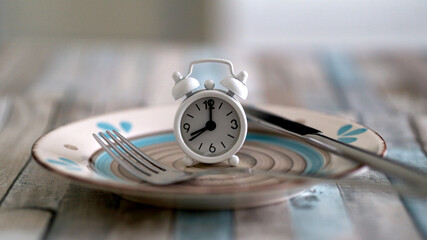 Close up view of alarm clock on a plate intermittent fasting diet concept , time to eat healthy...