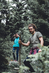 Couple spending active day outdoor, hiking through an evergreen forest in the mountains