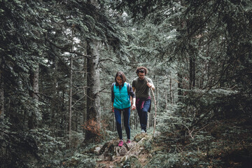 Obraz premium Couple hiking through an evergreen forest