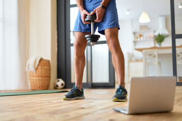 Athletic young man using notebook during workout at home