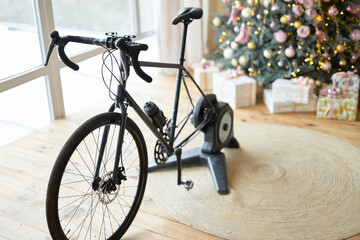 Fototapeta na wymiar Black exercise bicycle in apartment with Christmas tree