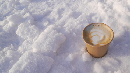 Paper cup with aromatic, hot latte coffee on fluffy, frosty snow. Aromatic composition with natural.
